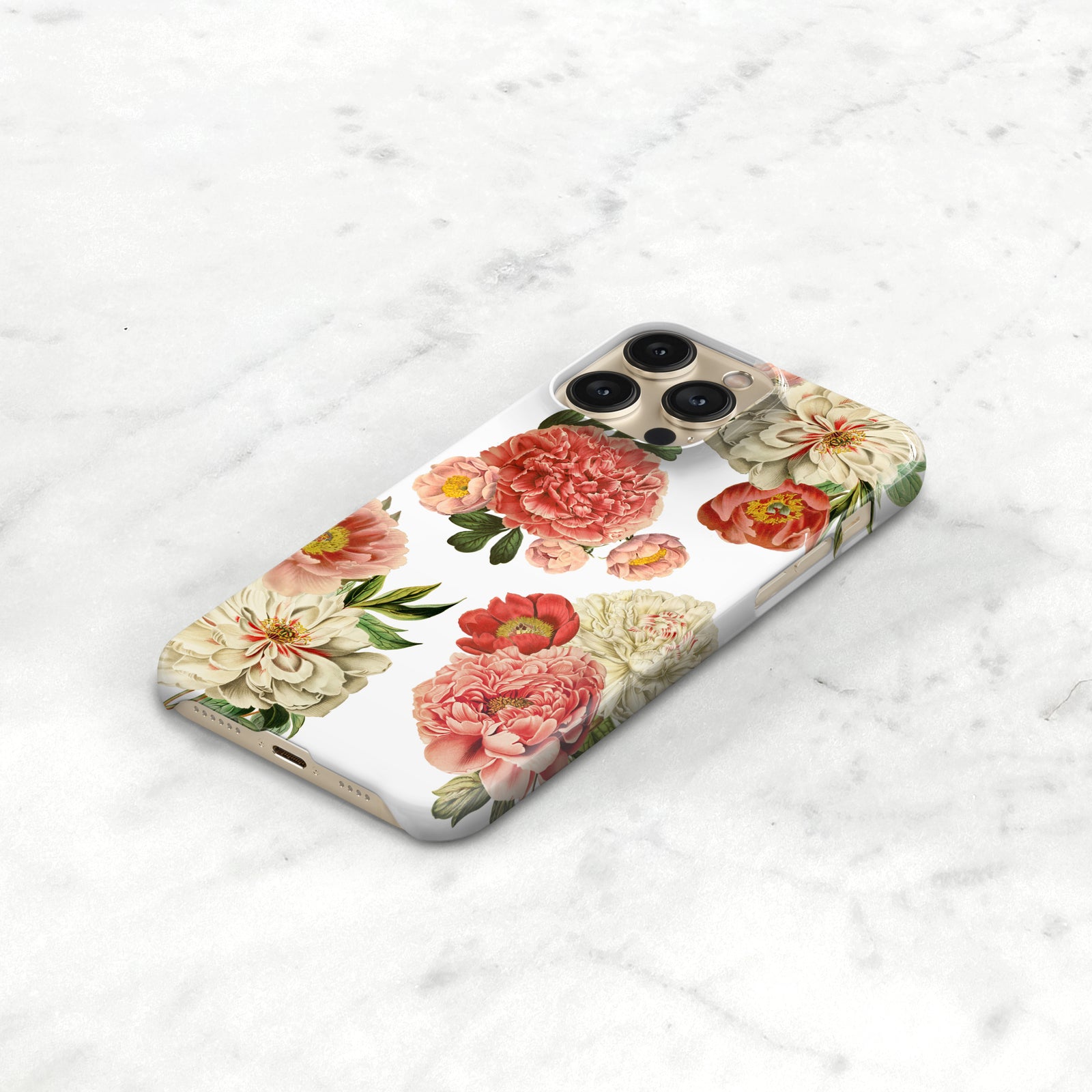 A white phone case with a floral design featuring pink and white flowers, including roses and peonies, is displayed on a marble surface.
