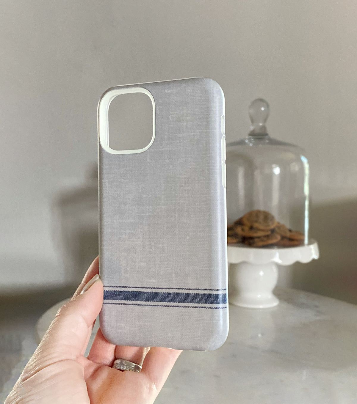 french stripe on gray linen iphone 11 pro case held in front of cookie platter