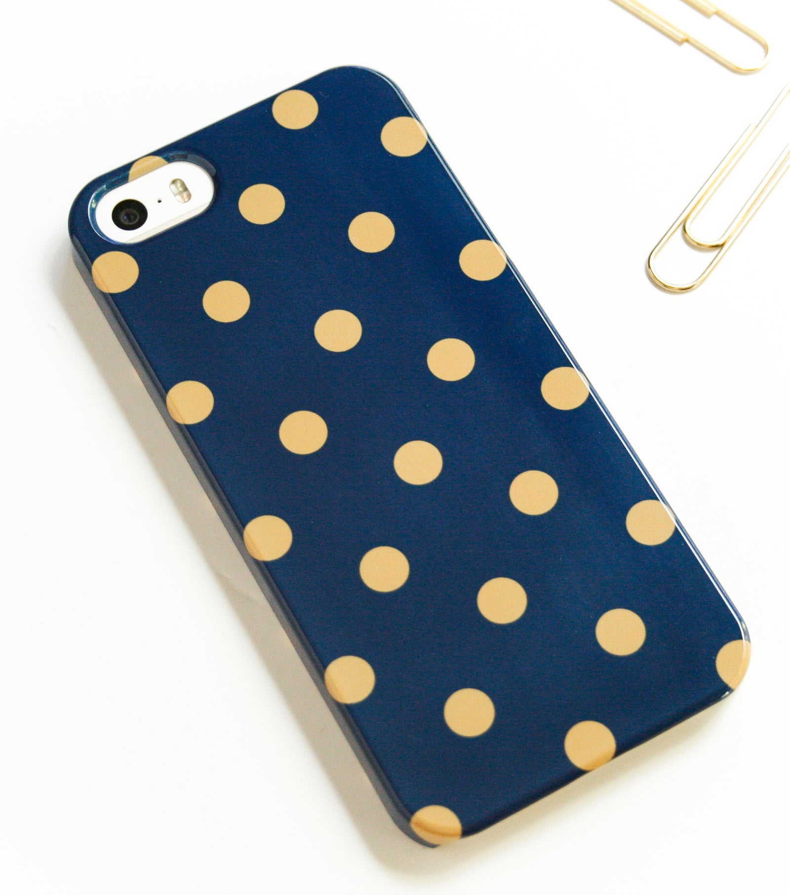 A blue phone case with yellow polka dots is placed on a white marble surface.